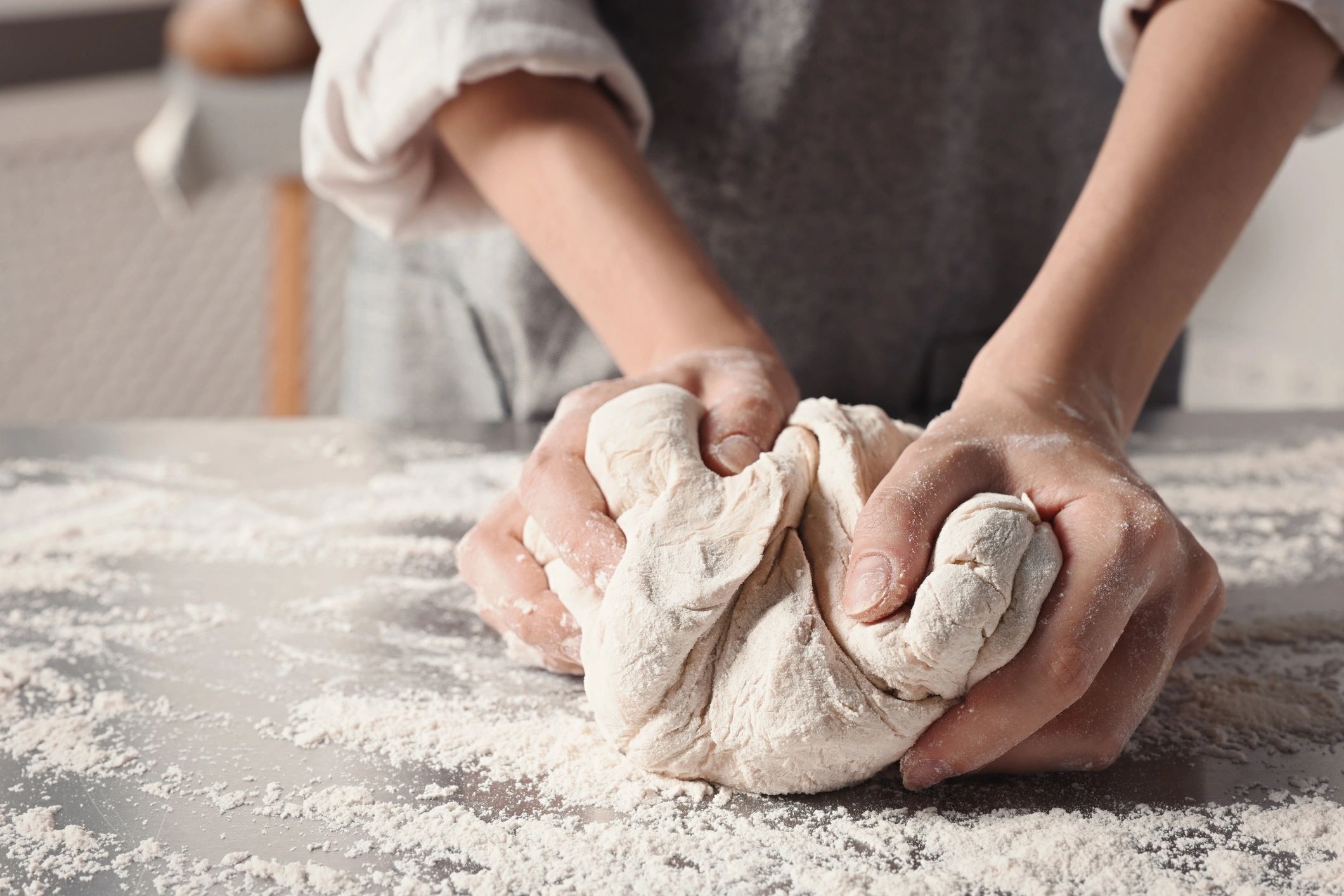 Closeup of hands kneading dough at a table